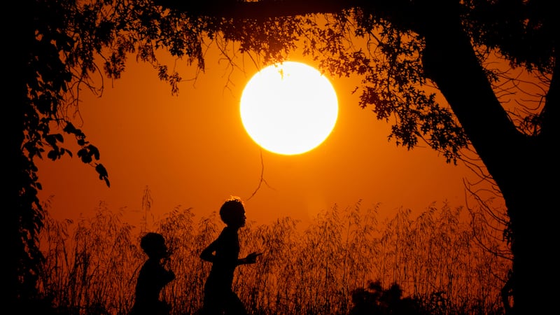 ARCHIVO - La silueta de dos personas, recortadas contra el cielo al atardecer en Shawnee...