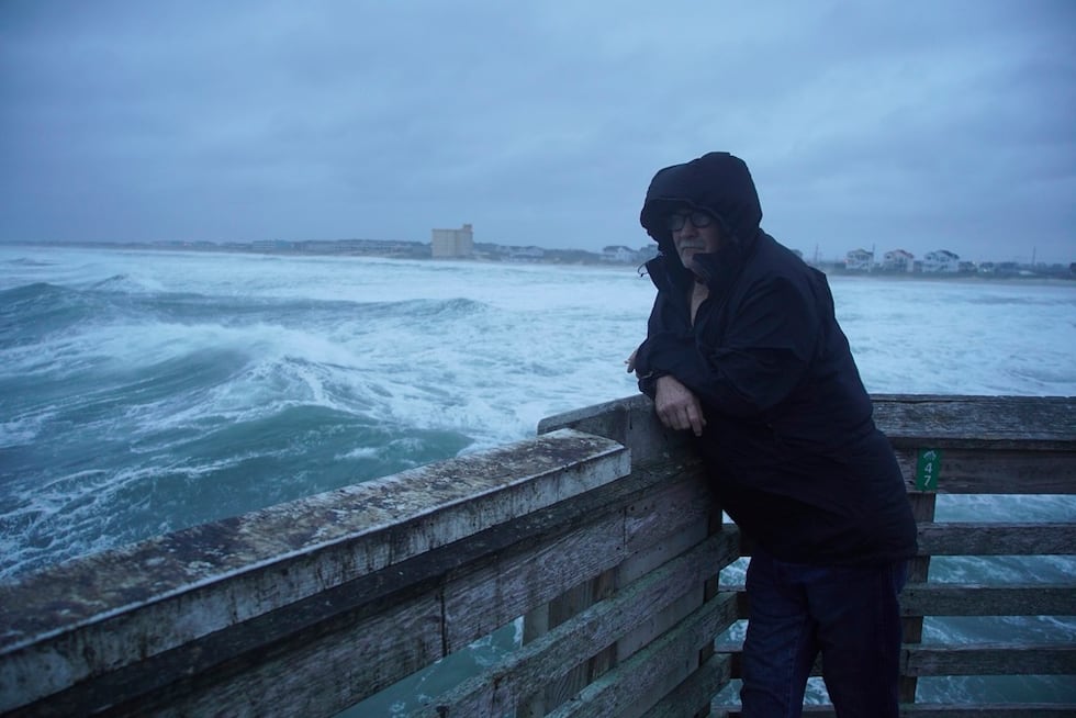 Un hombre se fuma un cigarrillo al final del muelle de Jennette mientras las olas del huracán...